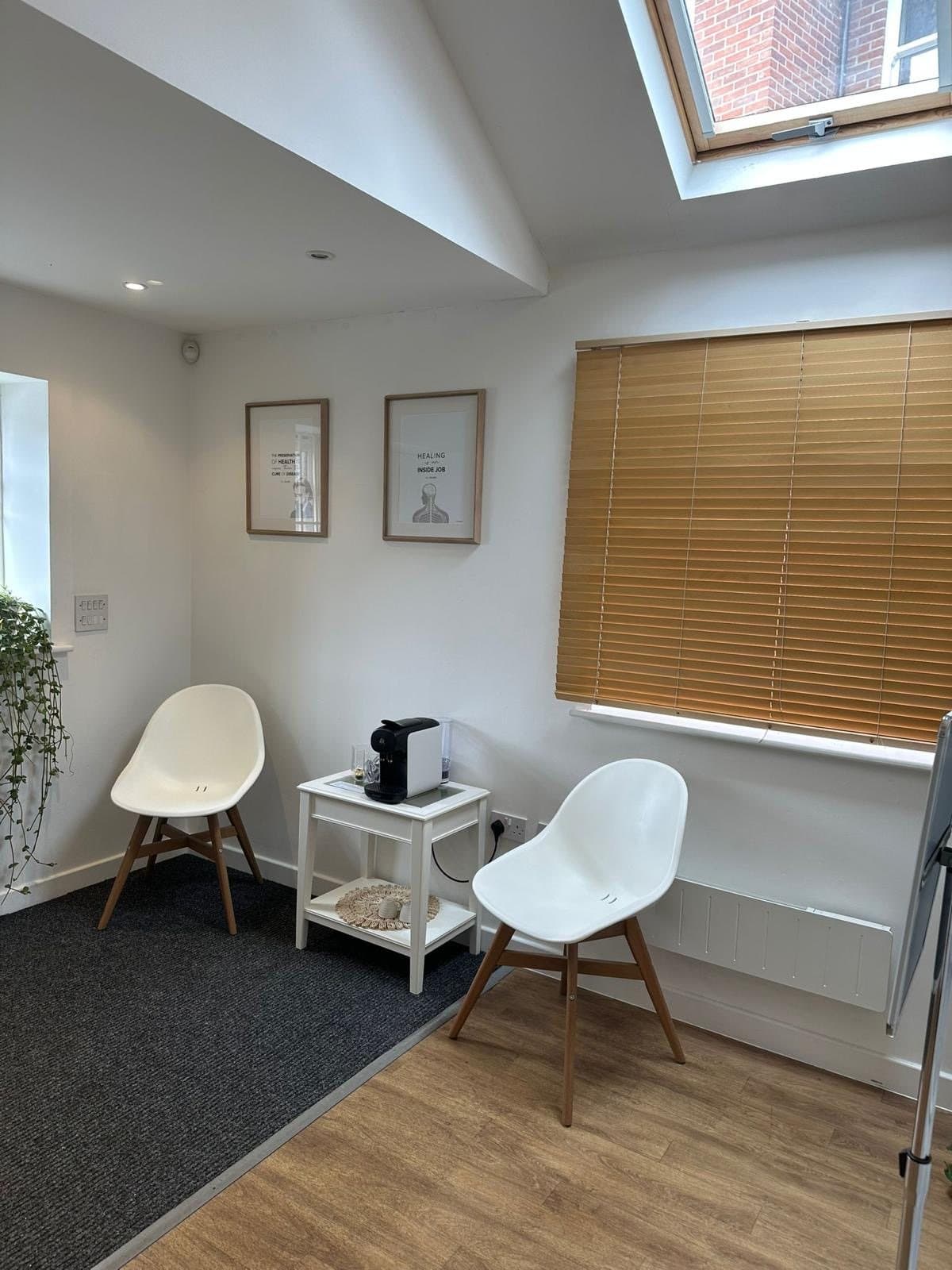 The clinic's waiting area with two chairs, a skylight and a coffee machine