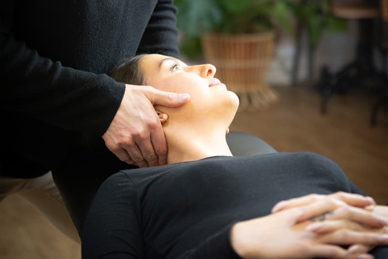 A patient lying face up receiving gentle treatment to the neck